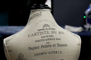 Back view of a vintage French mannequin with artistic text in a dark room.